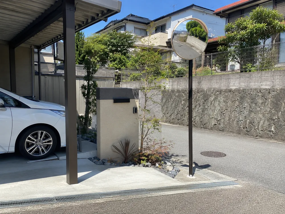 A garage mirror (orange round type) set on a pole at the driveway exit